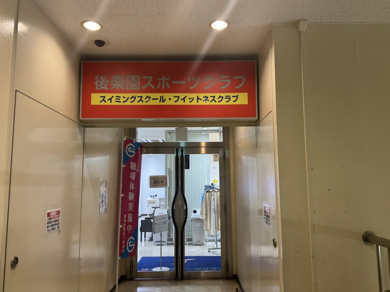 後楽園スポーツクラブ調布の2階入口とフィットネスクラブの看板