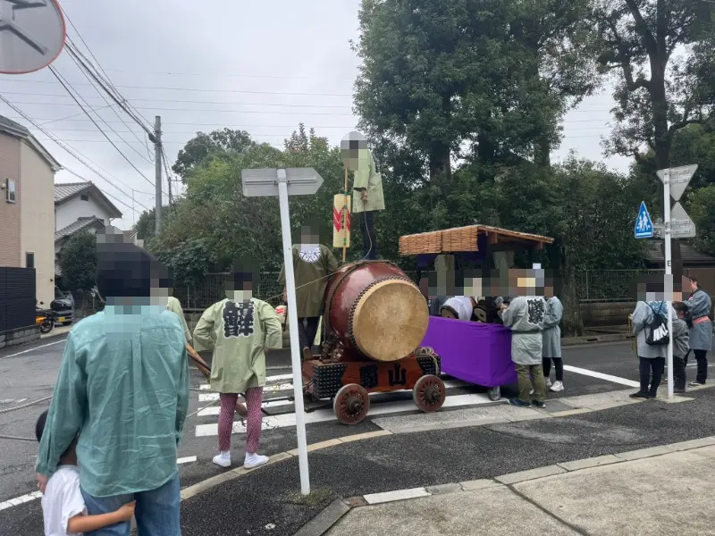 調布市深大寺の道路沿いで山車の太鼓を演奏する祭り関係者と見守る子どもたち】