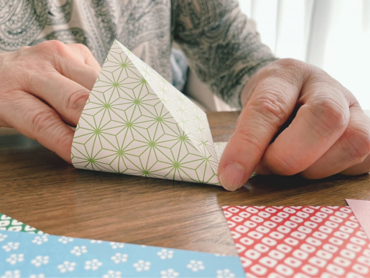 折り紙を折る高齢女性の手