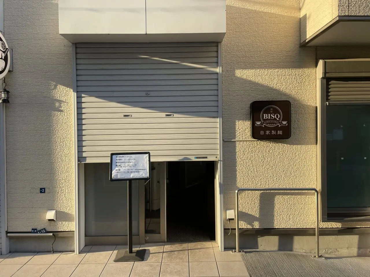 麺屋BISQ（ビスク）店頭。シャッター前に案内ボードが置かれています