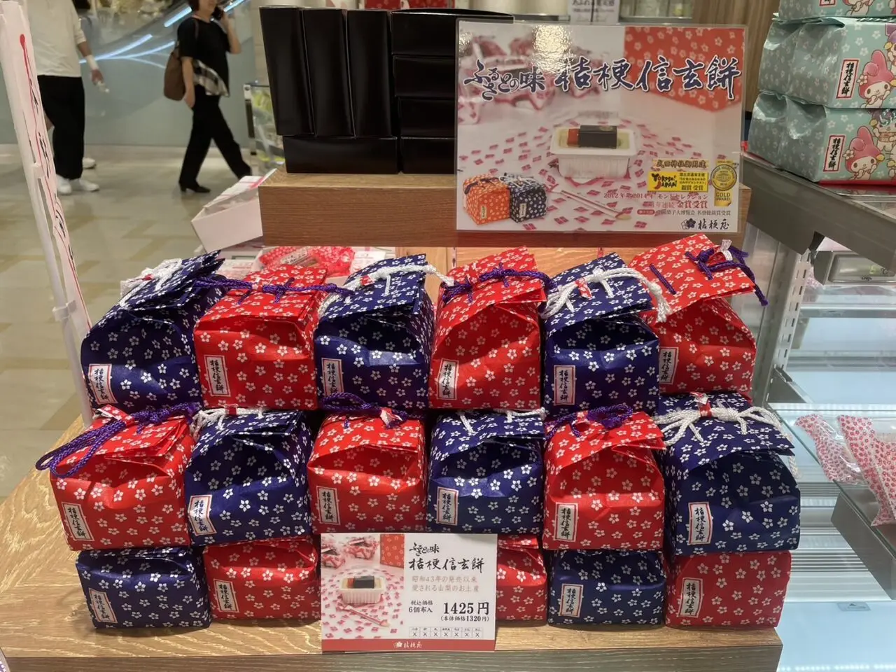 桔梗信玄餅の赤と紺の巾着包みが並ぶ販売棚