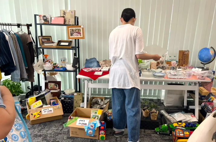 フリーマーケットブースに並んだ生活雑貨やおもちゃを手に取る来場者の様子