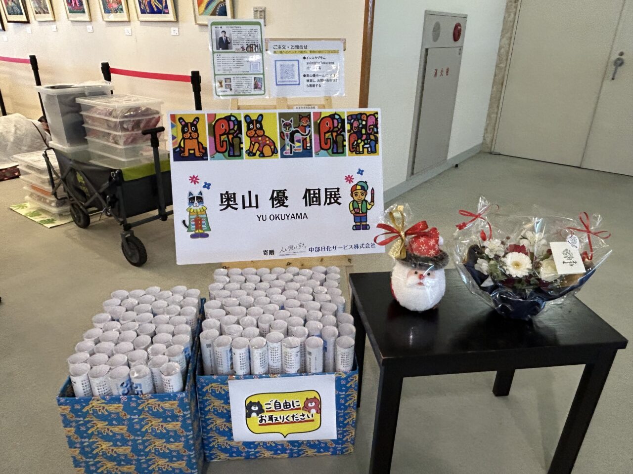 奥山優個展の会場に設けられたグッズ展示とチラシ配布コーナー