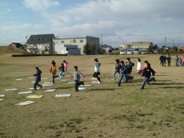 芝生広場で行われる巨大かるた大会の様子、札に向かって走る子どもたち
