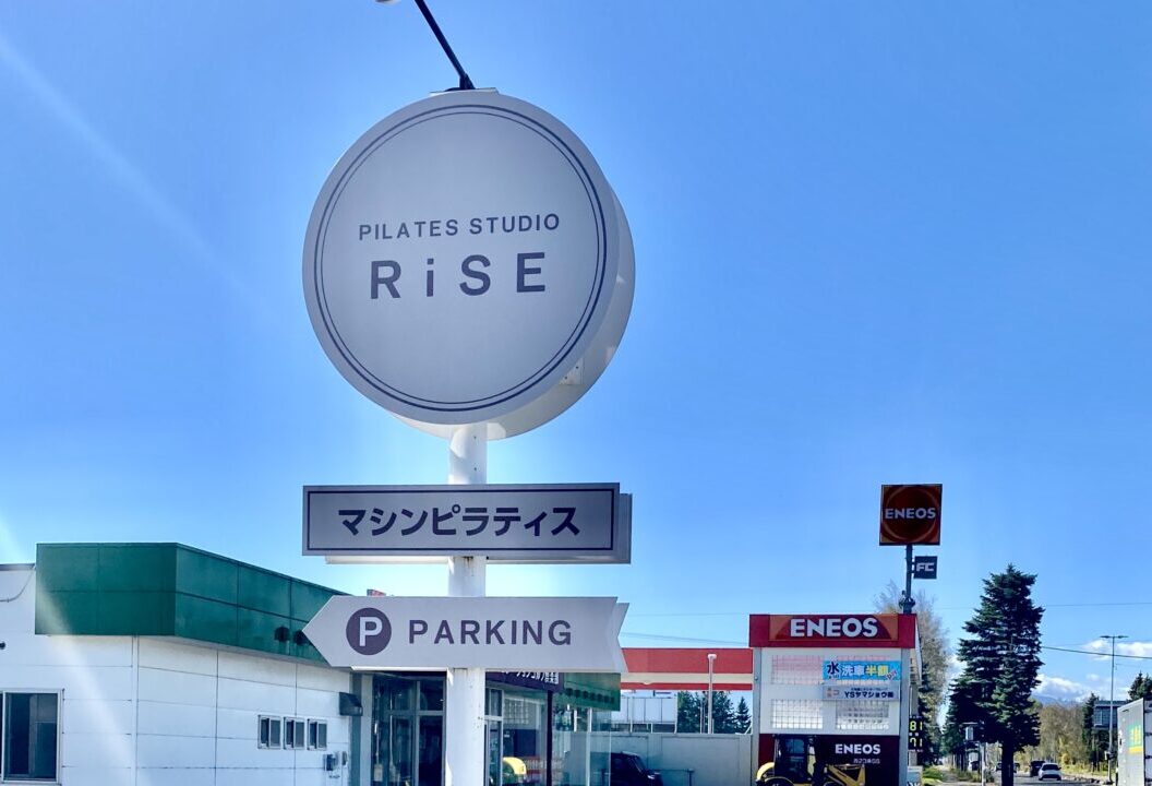店舗名 PILATES STUDIO RiSE　帯広店　住所 帯広市西23条南1丁目7番地Vita1F　営業時間 9:00~21:30 定休日 不定休 駐車場 店舗前10台　白い看板　ピラティススタジオRASEと記載されている素敵な看板と青空　新規オープン　新規開店　ニューオープン　オープン　開店　帯広ピラティス